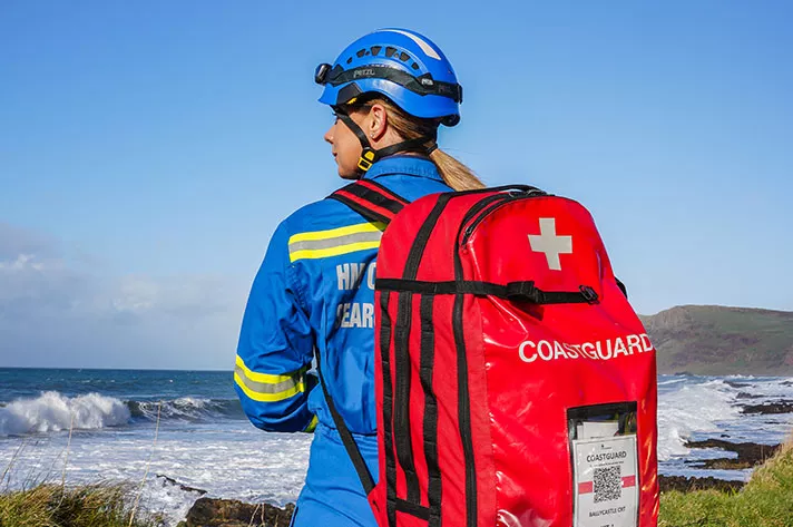 The back of a female coastguard rescue officer carrying a rescue bag